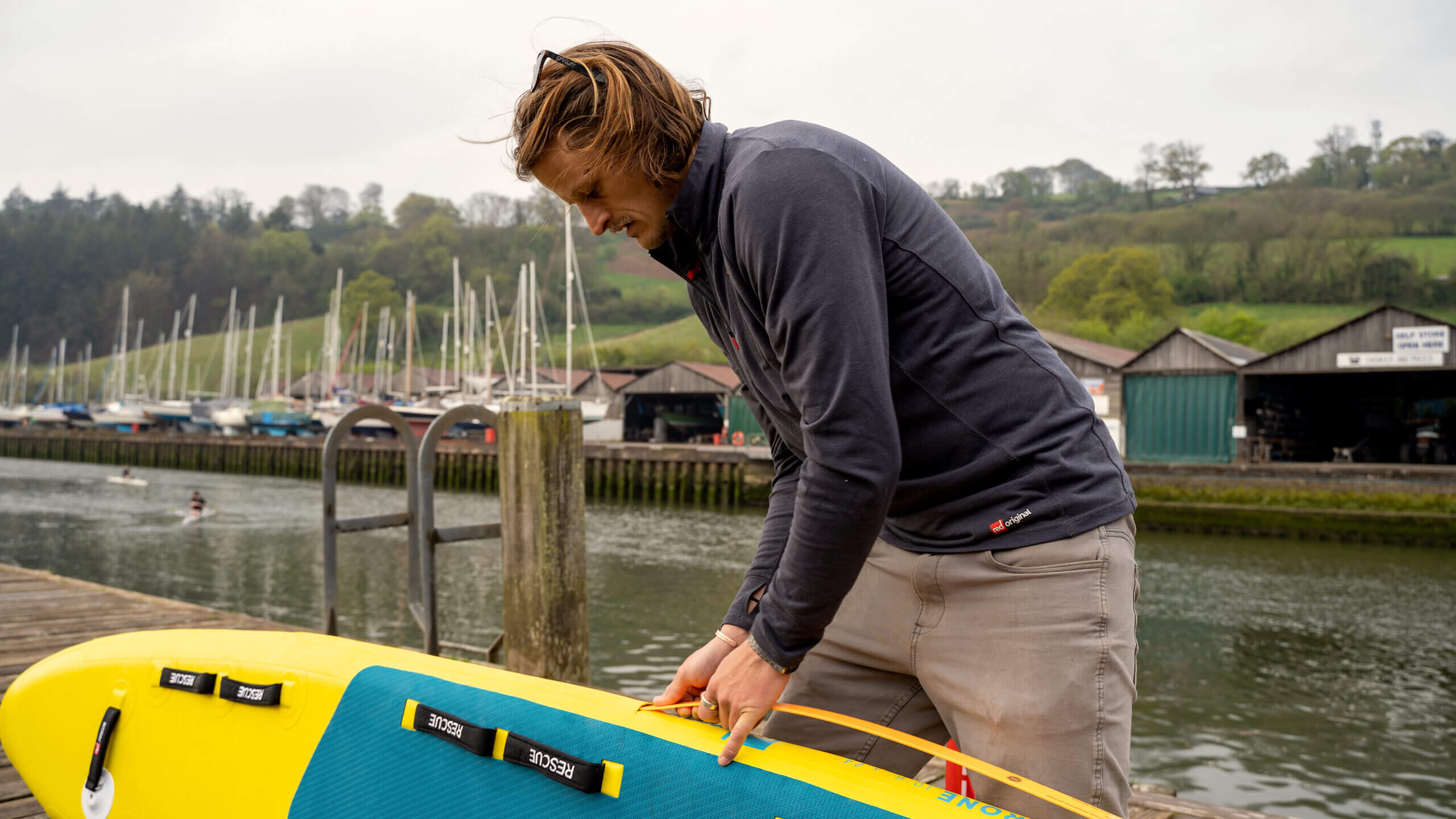 Lifeguard inserting RSS stiffening battens into rail of inflatable prone rescue surf board