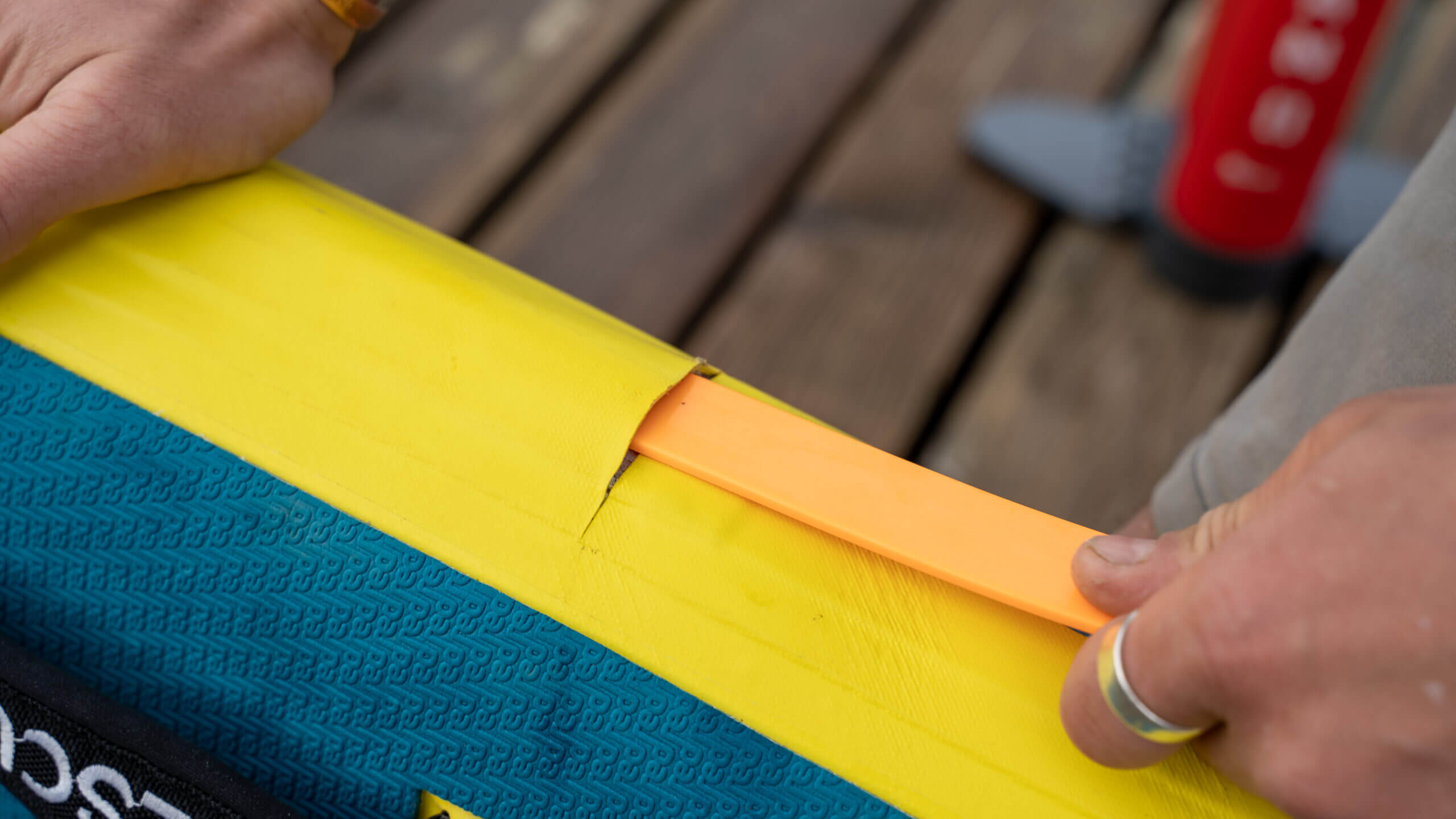 Lifeguard inserting RSS stiffening battens into rail of inflatable prone rescue surf board